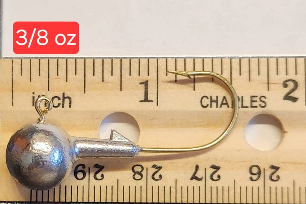 A fishing hook is shown on top of a ruler.