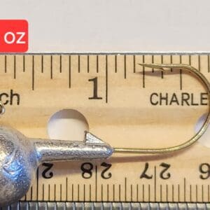 A fishing hook is shown on top of a ruler.