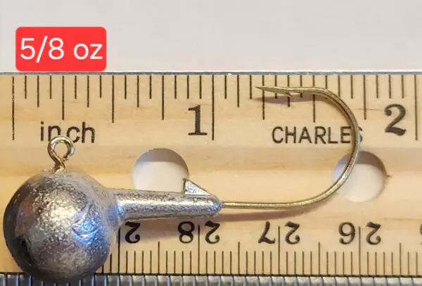 A fishing hook is shown on top of a ruler.