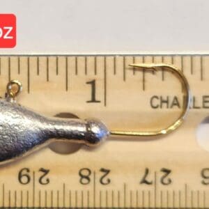 A fishing hook is shown on top of a ruler.