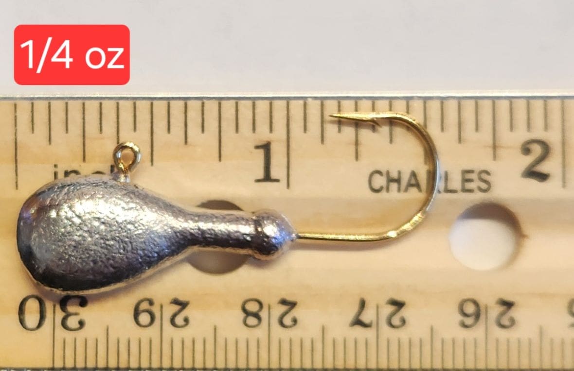 A fishing hook is shown on top of a ruler.