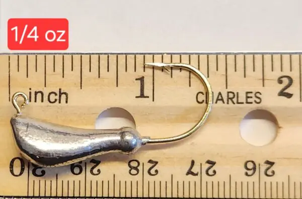 A fishing hook is shown on top of a ruler.