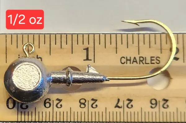 A wooden ruler with a metal fish hook and a small metal object.