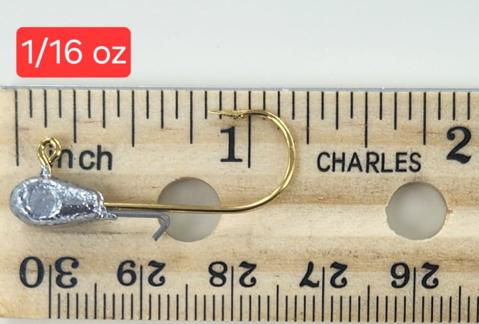 A fishing hook is sitting on top of a ruler.