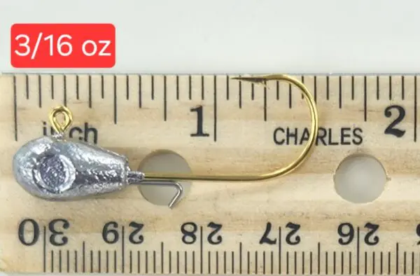 A fishing hook is shown on top of a ruler.