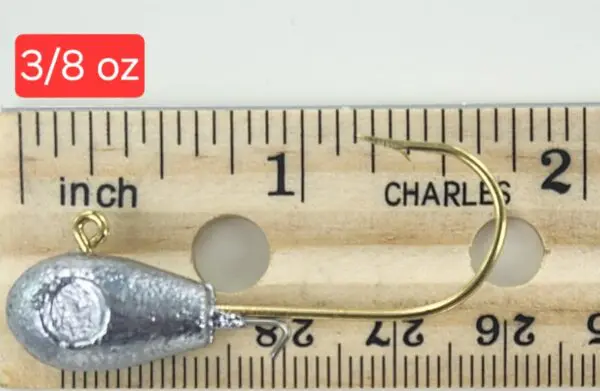 A wooden ruler with a fishing hook and a measuring tape.