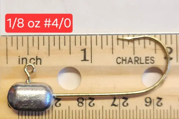 A wooden ruler with a metal fishing hook and a measuring tape.