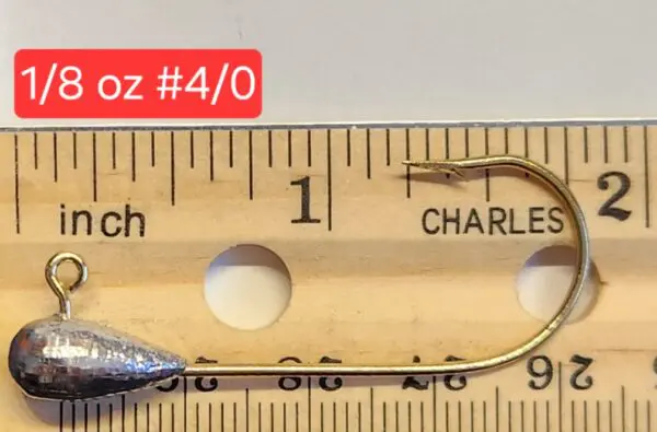 A wooden ruler with a fish hook and a measuring tape.