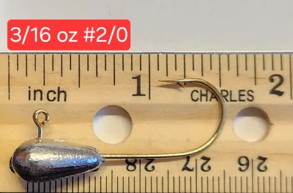 A fishing hook is shown on top of a ruler.