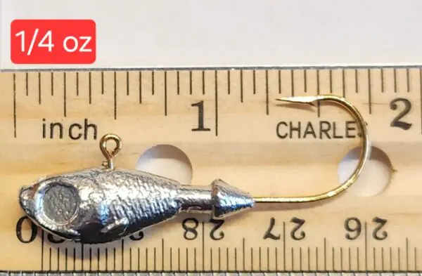 A fishing hook is on the ruler of length.