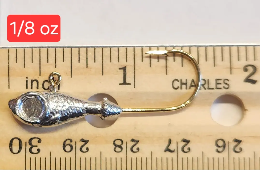 A fishing hook is shown on top of a ruler.