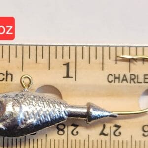 A small metal fish is on the ruler of inches.