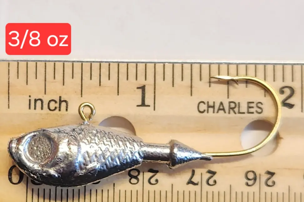 A small metal fish is on the ruler of inches.