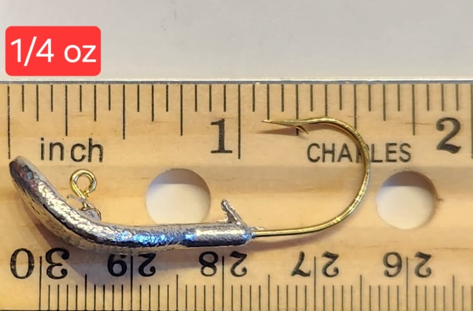 A fishing hook is on the ruler of length.