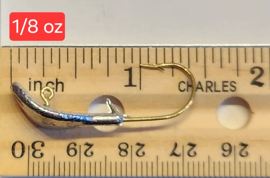 A fishing hook is shown on top of a ruler.