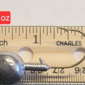 A metal ball and needle on top of a ruler.